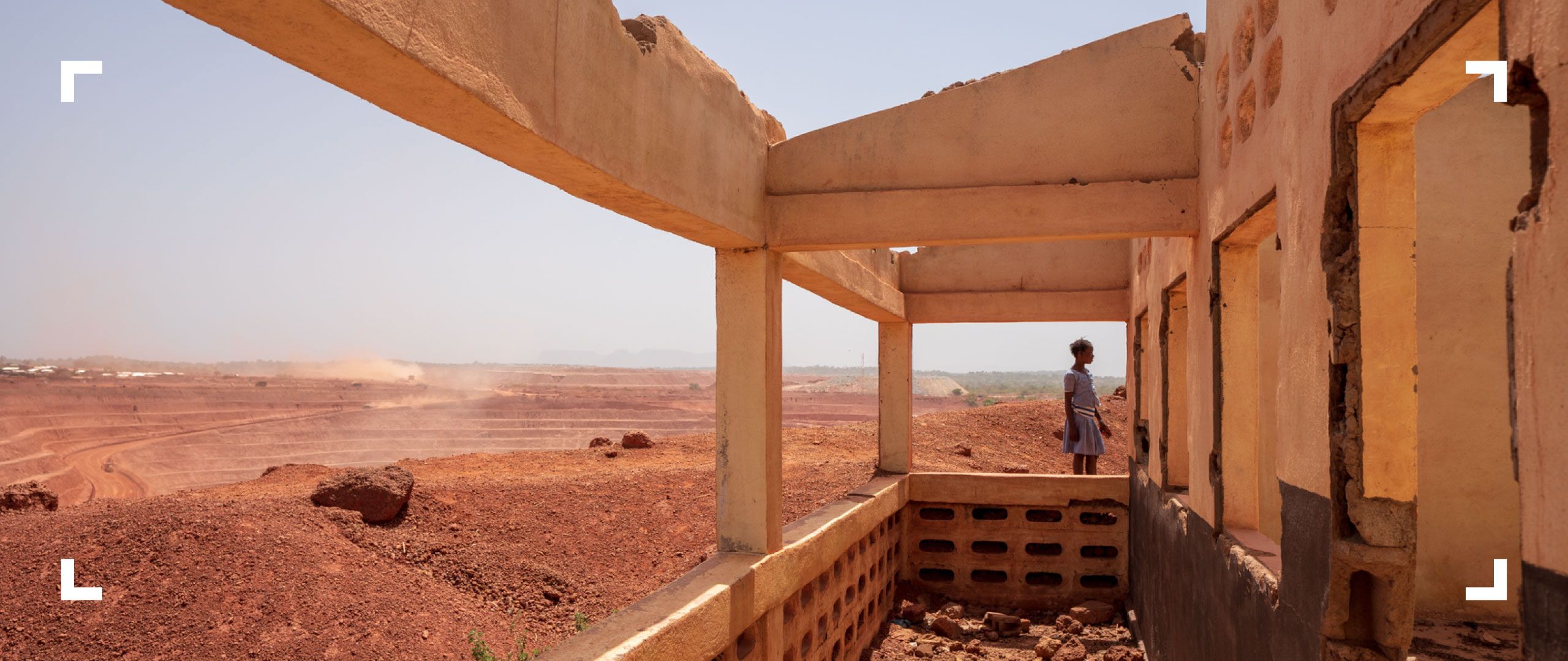 Photograph of a young girl standing beside an open-pit mine in Africa.
